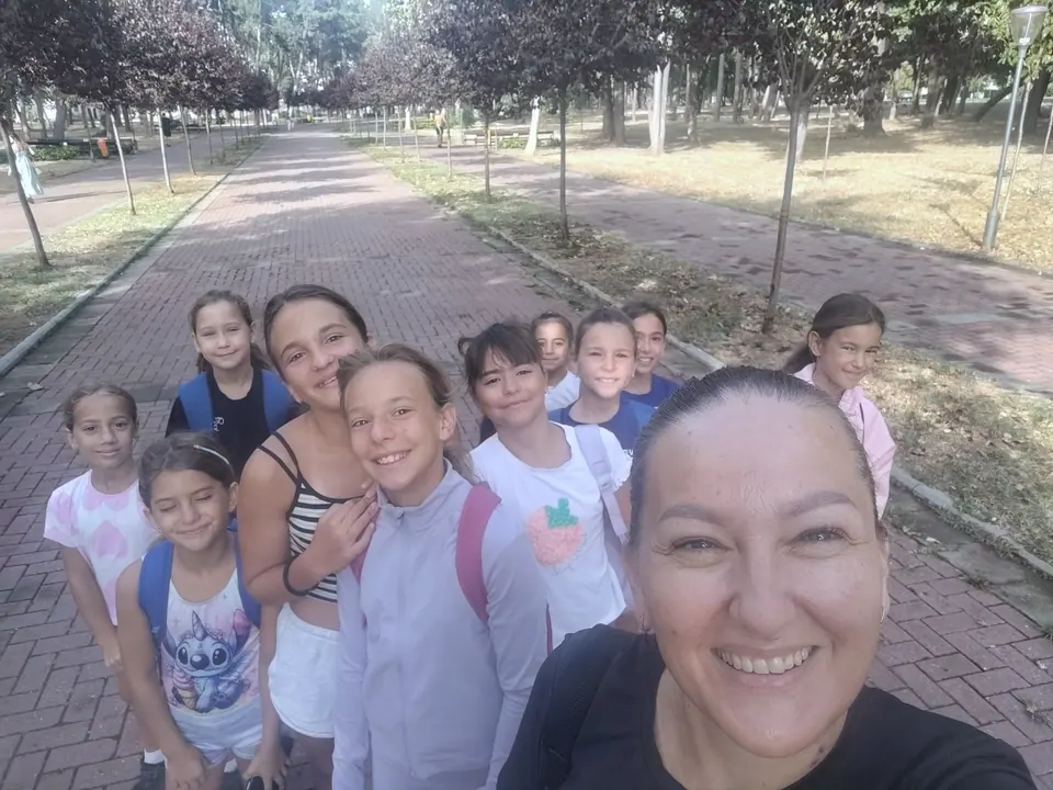 Trenerica pravi selfi sa grupom nasmejanih devojčica na stazi u parku